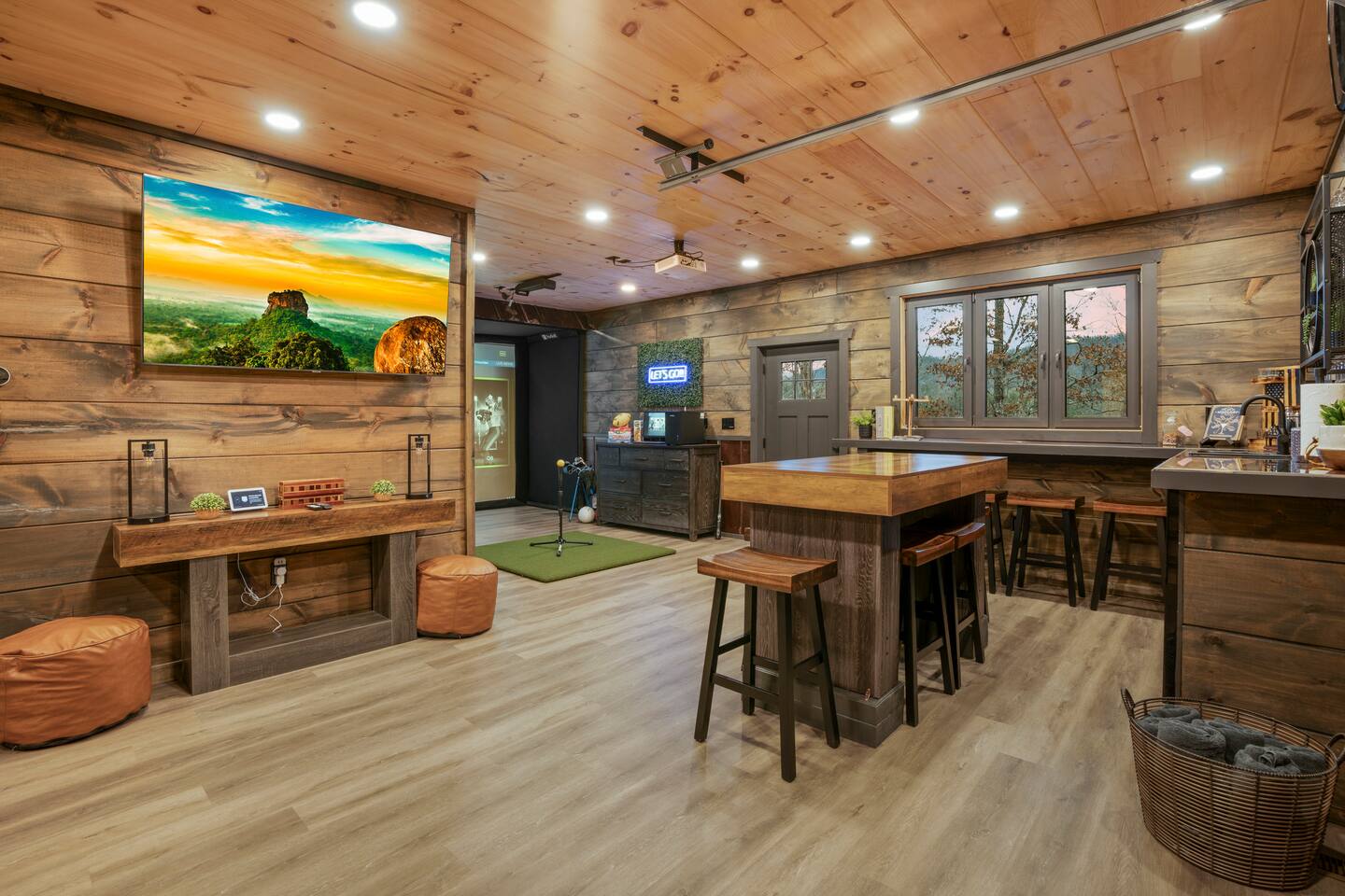 Open game room with bar-height table, stools, and wall TV