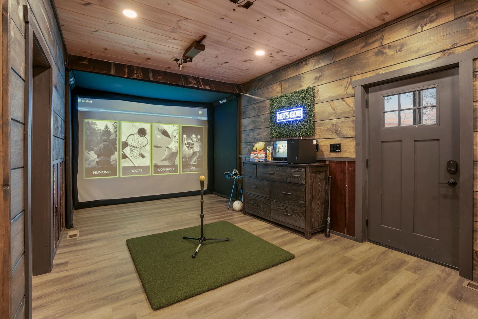 Multi-sport simulator room with large screen and turf hitting mat